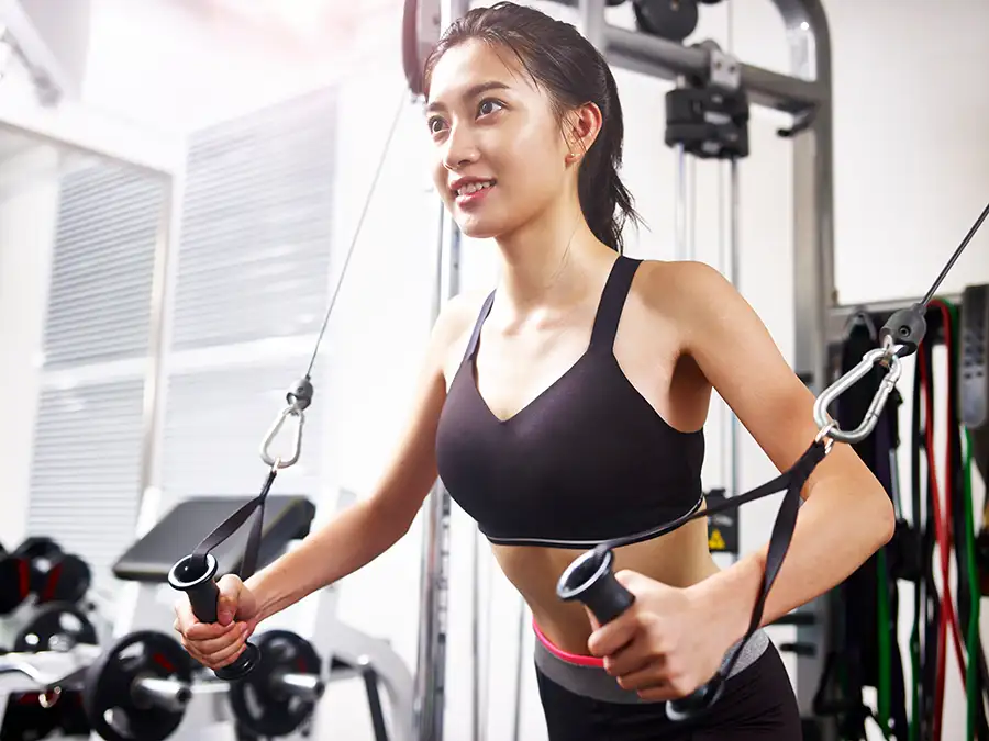 Young Asian American woman using resistance training equipment - Collinsville, IL - Bethalto, IL